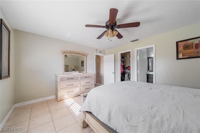 tiled bedroom featuring a walk in closet, ceiling fan, a closet, and ensuite bathroom