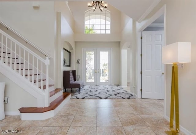 tiled foyer with a chandelier, a towering ceiling, and french doors