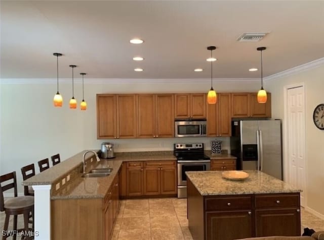 kitchen featuring sink, stainless steel appliances, light stone counters, pendant lighting, and a breakfast bar