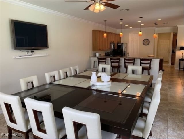 tiled dining space with ceiling fan and crown molding