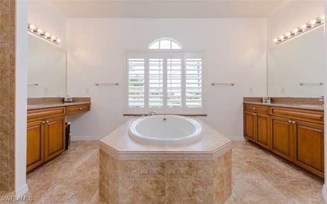 bathroom featuring tile patterned flooring, a relaxing tiled tub, and vanity