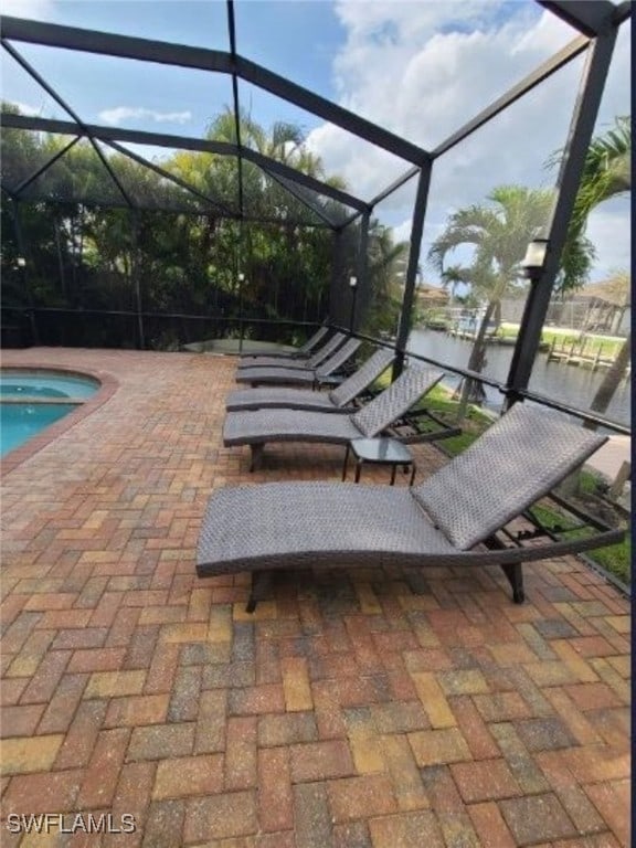 view of patio with glass enclosure and a water view