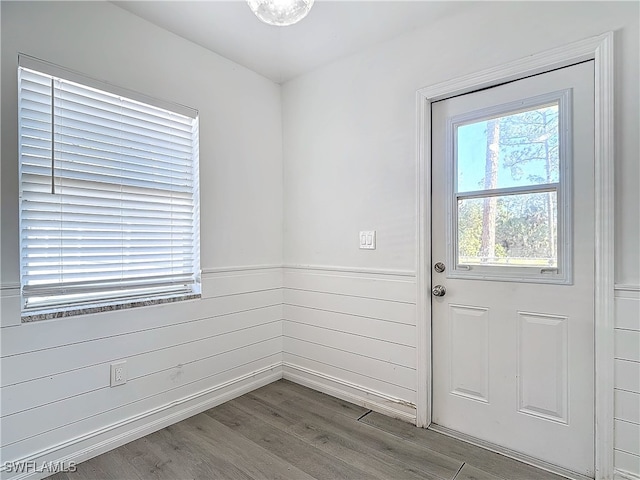 doorway with hardwood / wood-style flooring and wooden walls