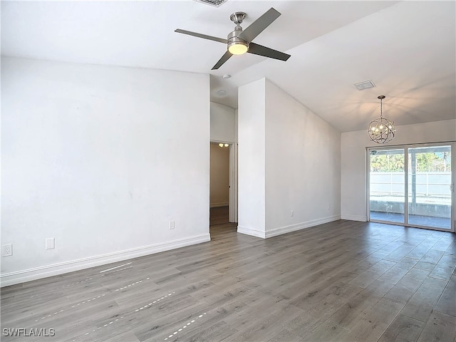 spare room featuring hardwood / wood-style floors, ceiling fan with notable chandelier, and lofted ceiling