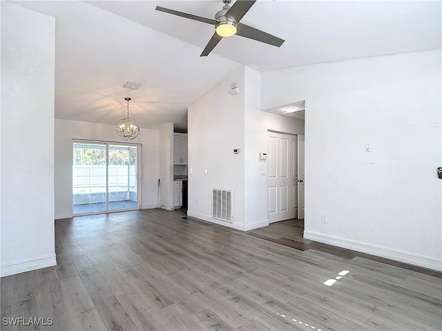 unfurnished living room with ceiling fan with notable chandelier, wood-type flooring, and lofted ceiling