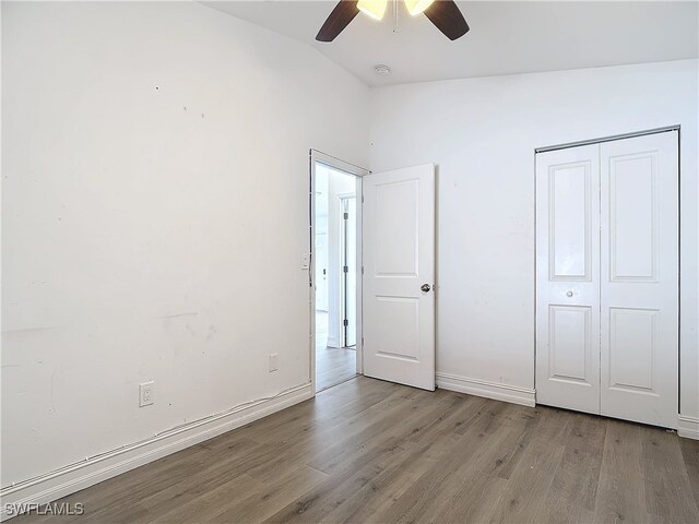 unfurnished bedroom with light wood-type flooring, a closet, vaulted ceiling, and ceiling fan