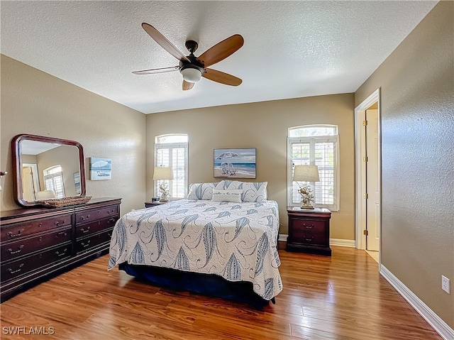 bedroom featuring ceiling fan, wood-type flooring, and a textured ceiling