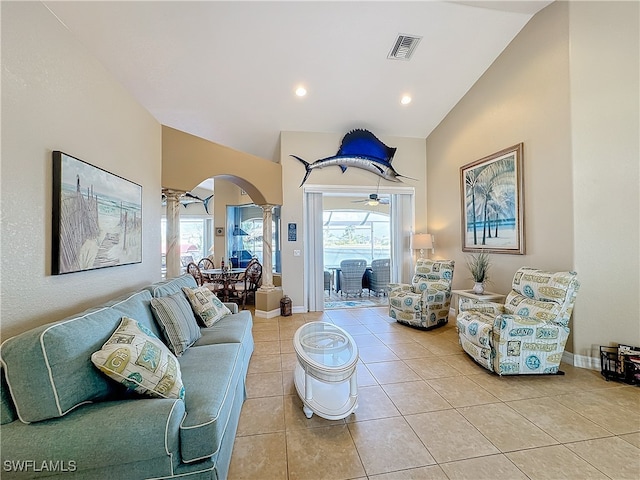 tiled living room with decorative columns and vaulted ceiling