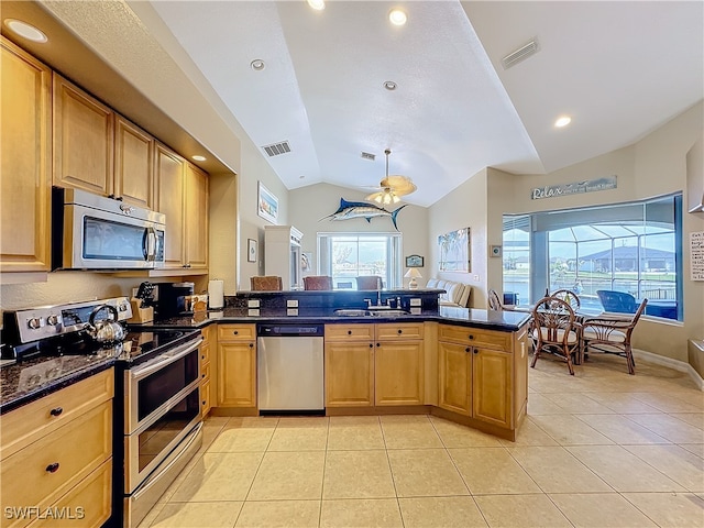 kitchen featuring sink, kitchen peninsula, vaulted ceiling, light tile patterned floors, and appliances with stainless steel finishes