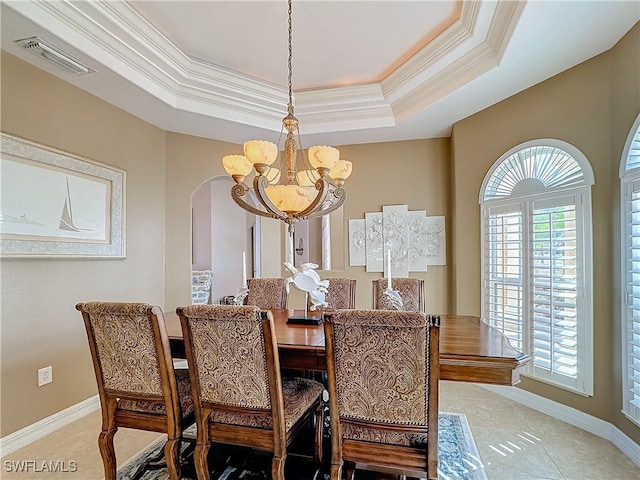 tiled dining space with a raised ceiling, ornamental molding, and an inviting chandelier