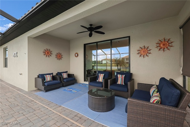 view of patio featuring ceiling fan, glass enclosure, and an outdoor living space