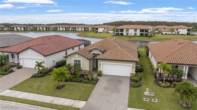 view of front of property featuring a front lawn, a garage, and a water view