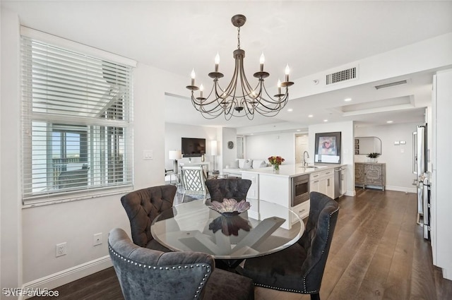 dining space featuring dark hardwood / wood-style floors, a notable chandelier, and sink