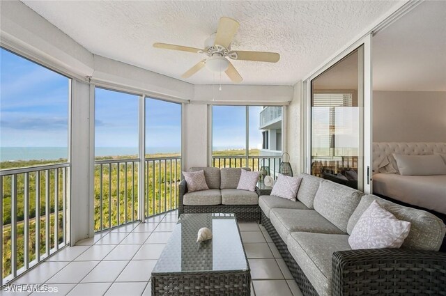 sunroom with a wealth of natural light, a water view, and ceiling fan