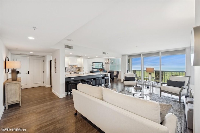 living room featuring floor to ceiling windows, sink, dark wood-type flooring, and a notable chandelier