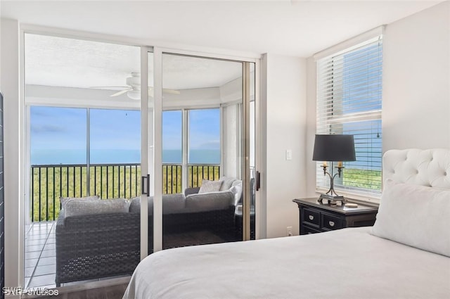 bedroom featuring multiple windows, ceiling fan, a water view, and wood-type flooring