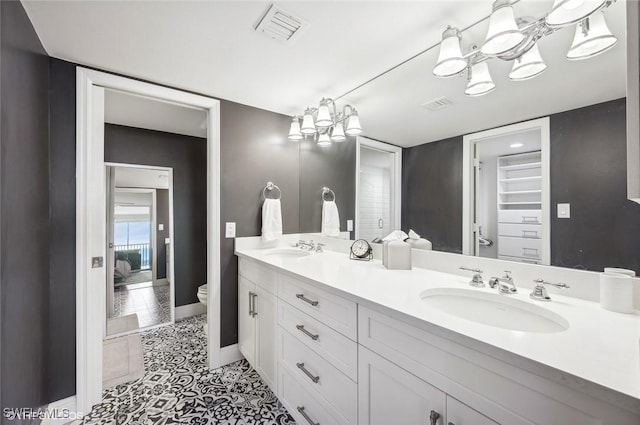 bathroom featuring tile patterned floors, an inviting chandelier, vanity, and toilet