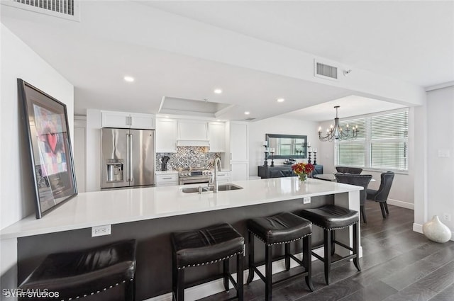 kitchen with a kitchen breakfast bar, dark wood-type flooring, sink, high quality appliances, and white cabinetry