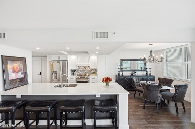 kitchen with a kitchen bar, sink, white cabinetry, and stainless steel appliances