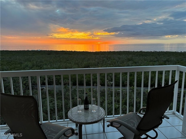 balcony at dusk featuring a water view