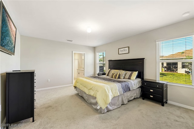 bedroom featuring light carpet and connected bathroom