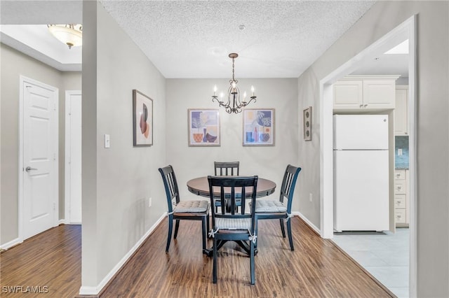 900 Arbor Lake Dr Unit 9-101, Naples, FL 34110 - dining room featuring a chandelier, wood finished floors, baseboards, and a textured ceiling