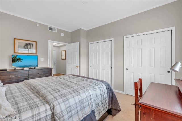 bedroom with crown molding, two closets, and light carpet