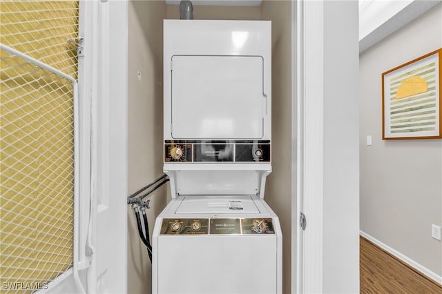 laundry room with hardwood / wood-style floors and stacked washing maching and dryer