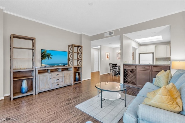 living room with crown molding, hardwood / wood-style floors, and a skylight