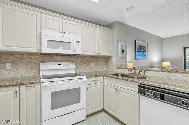 kitchen featuring white appliances, decorative backsplash, a sink, and light tile patterned flooring