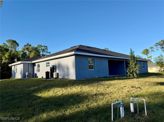 rear view of property with a yard and central air condition unit