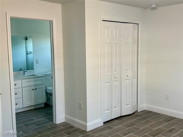 unfurnished bedroom with ensuite bath, a closet, and sink