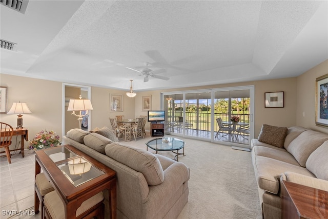 carpeted living room with a tray ceiling, ceiling fan, and a textured ceiling