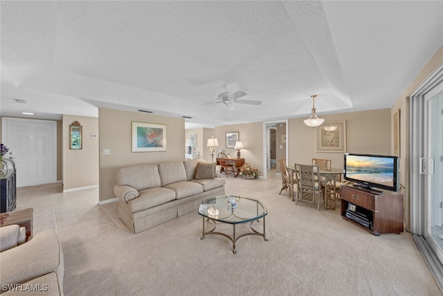 carpeted living room featuring a textured ceiling, a raised ceiling, and ceiling fan