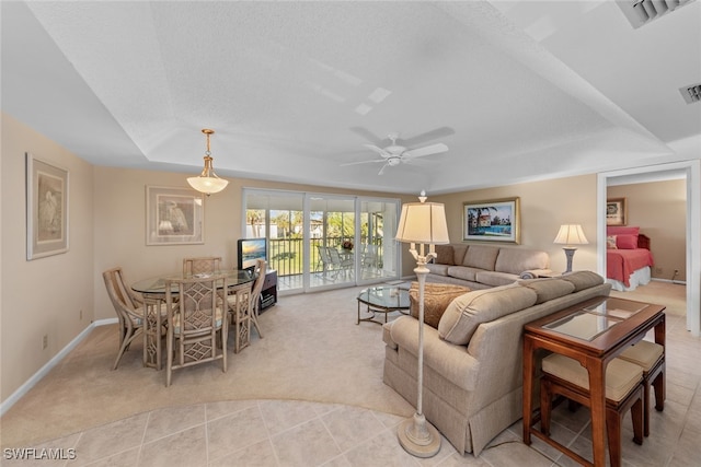 carpeted living room featuring ceiling fan, a textured ceiling, and a tray ceiling