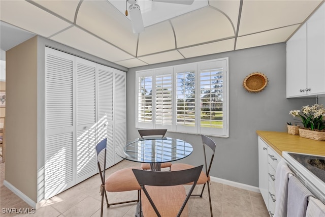 dining space with light tile patterned floors, a paneled ceiling, and ceiling fan