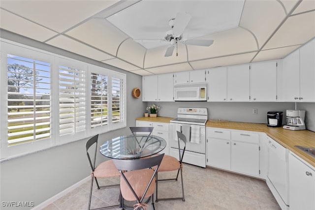 kitchen featuring white appliances, white cabinetry, a healthy amount of sunlight, and light tile patterned flooring