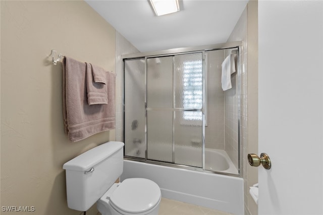 bathroom with toilet and shower / bath combination with glass door