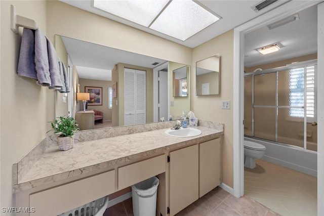 full bathroom featuring tile patterned floors, vanity, bath / shower combo with glass door, and toilet