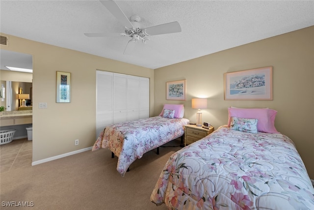 bedroom featuring a textured ceiling, a closet, ceiling fan, and light colored carpet