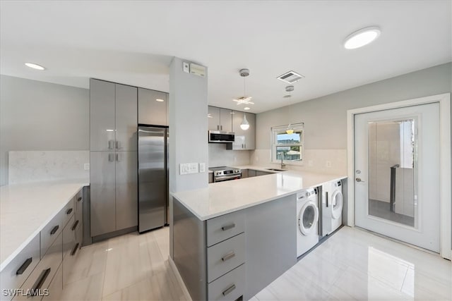 kitchen with pendant lighting, gray cabinets, separate washer and dryer, appliances with stainless steel finishes, and kitchen peninsula