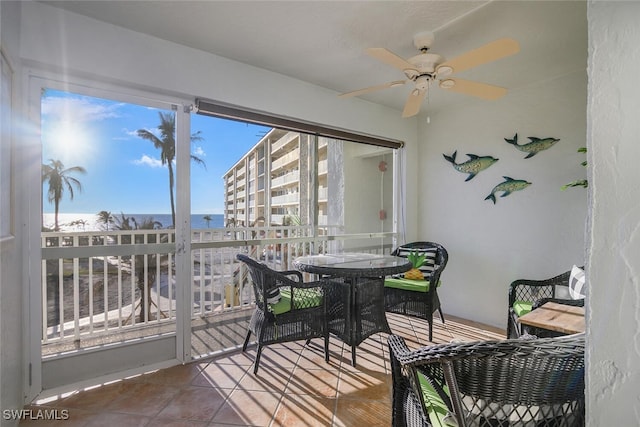 sunroom featuring ceiling fan and a water view