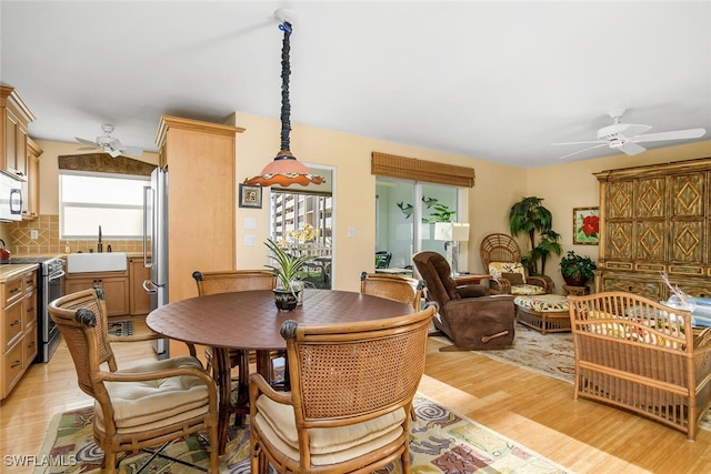 dining room with light hardwood / wood-style floors, ceiling fan, and sink