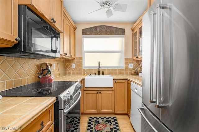 kitchen with tile countertops, decorative backsplash, sink, and appliances with stainless steel finishes