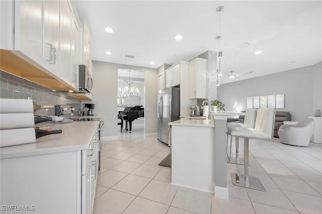 kitchen with hanging light fixtures, white cabinets, stainless steel appliances, and sink