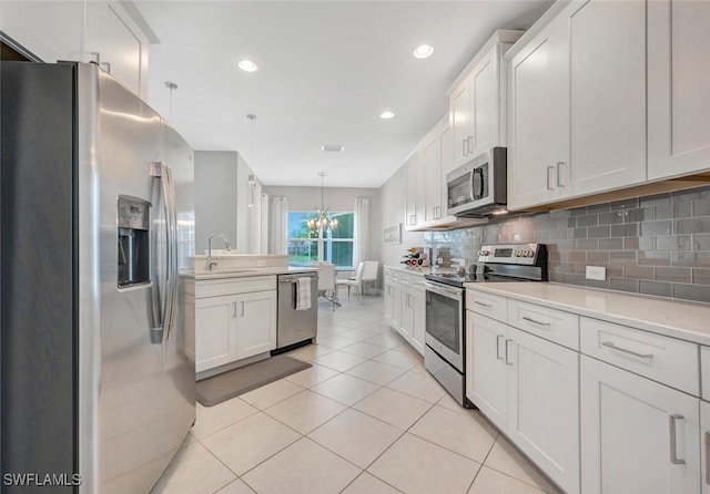 kitchen featuring pendant lighting, white cabinets, sink, and stainless steel appliances