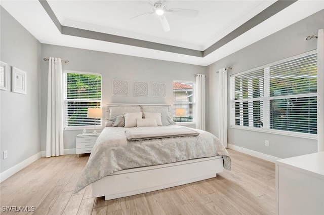 bedroom with light hardwood / wood-style flooring, a raised ceiling, ceiling fan, and crown molding