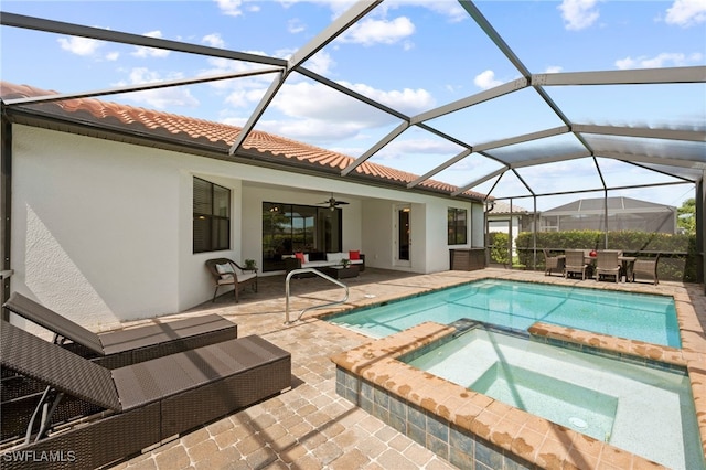 view of pool featuring outdoor lounge area, ceiling fan, a lanai, a patio area, and an in ground hot tub