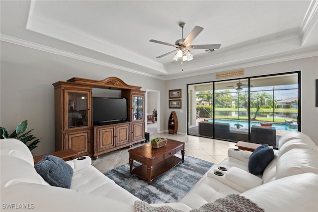 living room featuring a raised ceiling, light tile patterned floors, and ornamental molding