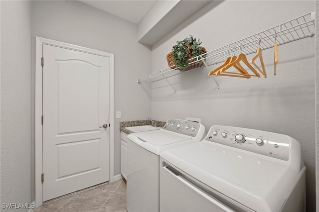 laundry area featuring washing machine and clothes dryer, sink, light tile patterned flooring, and cabinets